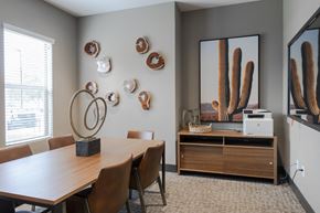 Phoenix apartment for rent - a conference room with a table and chairs and a mirror and cactus wall art