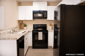 Reno apartment for rent - A black refrigerator is on the right in a kitchen with white cabinets.