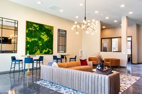 Reno apartment for rent - A modern living room with a large painting of a tree on the wall and a striped sofa in the center.