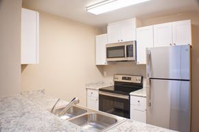 Reno apartment for rent - A kitchen with a sink, stove, oven, microwave, and refrigerator.