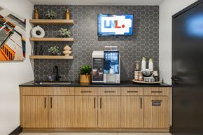 Kansas City apartment for rent - A kitchen with wooden cabinets and a counter with a coffee machine and a plant on it.