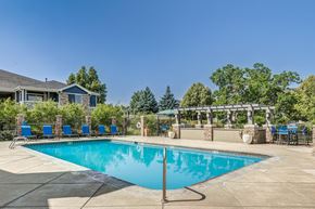 Fort Collins apartment for rent - a swimming pool with blue chairs around it and a house in the background