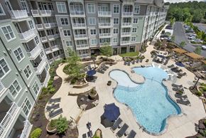 Kennesaw apartment for rent - An aerial view of a pool and patio area in front of a large apartment building.