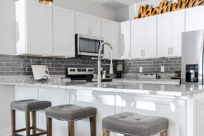 Nashville apartment for rent - a kitchen with white cabinets and a counter with three stools
