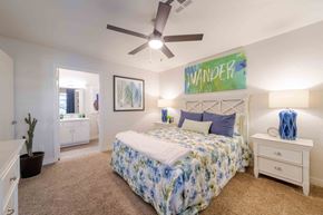 Phoenix apartment for rent - A bedroom with a bed, nightstand, and a ceiling fan.