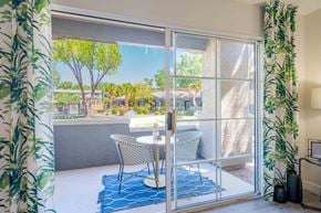 Phoenix apartment for rent - A patio with a table and chairs is visible through a sliding glass door.