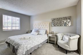 Tuscon apartment for rent - A bedroom with a bed, chair, and window.