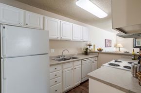 Colorado Springs apartment for rent - a kitchen with white cabinets and a sink and a refrigerator