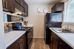 Olympia apartment for rent - A kitchen with dark wood cabinets and black appliances.