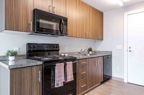 Hillsboro apartment for rent - A kitchen with a black stove top oven and a black microwave above it.