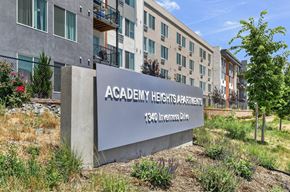 Colorado Springs apartment for rent - A concrete sign that says Academy Heights Apartments stands in front of a building.