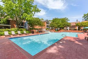 Newport News apartment for rent - A large swimming pool surrounded by a brick patio and lounge chairs.