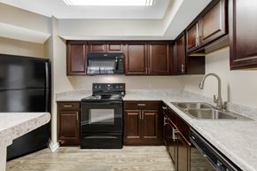 Newport News apartment for rent - A kitchen with a black oven and brown cabinets.