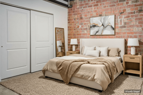 St Louis apartment for rent - A bedroom with a brick wall and a bed with a beige comforter.