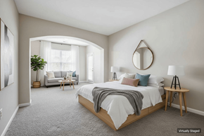 Pikesville apartment for rent - A bedroom with a large bed and a couch in the background.