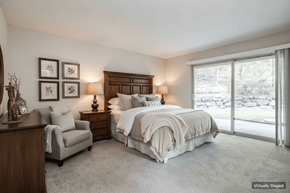 Tacoma apartment for rent - A bedroom with a large bed, a chair, and a nightstand with a lamp.