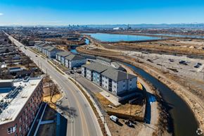 Commerce City apartment for rent - A road with a bridge over a river and a building on the right.