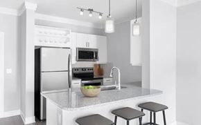 Overland Park apartment for rent - A modern kitchen with a refrigerator, microwave, oven, sink, and bar stools.
