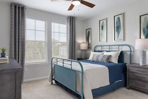 Charlotte apartment for rent - A bedroom with a bed, nightstand, and a ceiling fan.