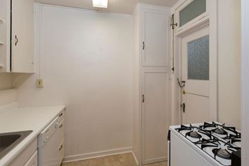 Colorado Springs apartment for rent - A small kitchen with a white stove and cabinets.