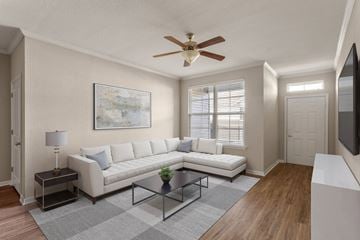 Greenville apartment for rent - A living room with a white couch, a painting on the wall, and a ceiling fan.