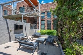 Nashville apartment for rent - A patio with a table and chairs is in front of a brick building.