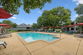 Smyrna apartment for rent - A pool surrounded by trees and umbrellas.