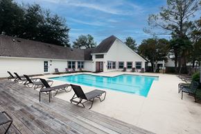 Pearl apartment for rent - a swimming pool with chairs and a house in the background