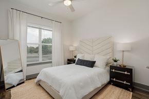 Nashville apartment for rent - A bedroom with a large bed, a dresser, and a window with white curtains.