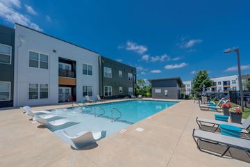 Nashville apartment for rent - A swimming pool surrounded by sun loungers in front of a building.