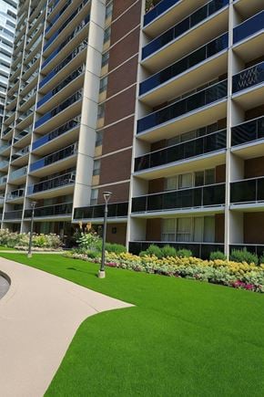 Toronto apartment for rent - A tall building with balconies and a green lawn in front.