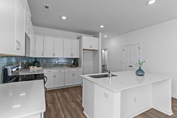 Leland townhouse for rent - A modern kitchen with white cabinets and a large island.