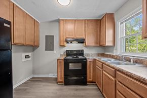 Jacksonville apartment for rent - A kitchen with wooden cabinets and a black fridge.