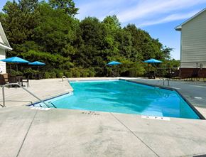 Fayetteville apartment for rent - A swimming pool surrounded by trees and a house.
