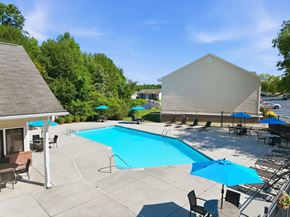 Fayetteville apartment for rent - A pool area with a blue pool and a white building.