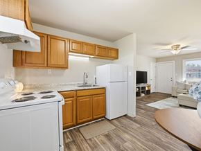 Jacksonville apartment for rent - A kitchen with a white stove top oven and a white refrigerator with wooden cabinets.