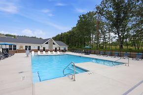 Sanford apartment for rent - A large outdoor swimming pool with a diving board and a building in the background.