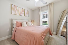 Sanford apartment for rent - A bedroom with a bed covered in a pink sheet and a ceiling fan.