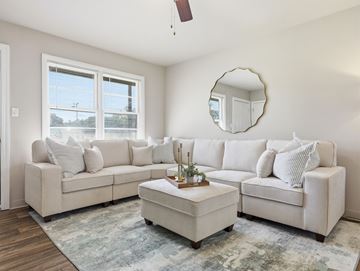 Jacksonville apartment for rent - A living room with a white couch and a round mirror on the wall.