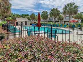 West Columbia townhouse for rent - A pool surrounded by red umbrellas and green chairs.
