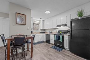 Kernersville apartment for rent - A kitchen with a black refrigerator and wooden dining table.