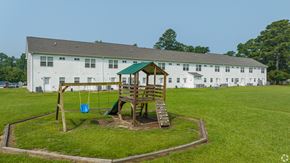 Jacksonville apartment for rent - a playground with a swing set in front of a white building
