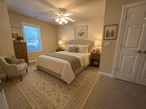 Huntersville triplex for rent - A bedroom with a bed, chair, and ceiling fan.