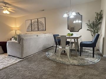 Fayetteville apartment for rent - A living room with a grey couch, a small table with chairs, and a rug on the floor.