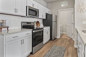 Longs apartment for rent - A kitchen with white cabinets and black appliances.