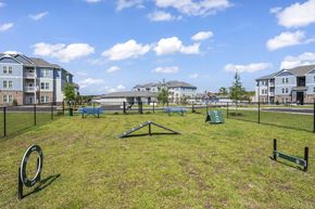 Longs apartment for rent - A playground with a slide, swings, and a seesaw in the foreground with apartment buildings in the background.