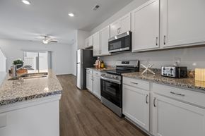 Leland townhouse for rent - A kitchen with white cabinets and a granite countertop.