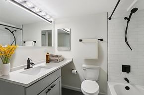 Boston apartment for rent - A white toilet is in a bathroom with a white sink and a white tub.