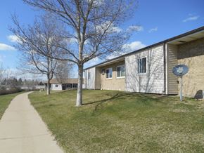 Dickinson apartment for rent - A grassy area in front of a building with a tree and a satellite dish.