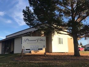 Dickinson apartment for rent - A sign for Pleasant Valley Apartments is in front of a building.